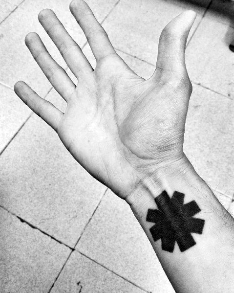 Minimalist black Red Hot Chili Peppers logo tattoo on the wrist, creating a bold and simple statement for dedicated fans.
