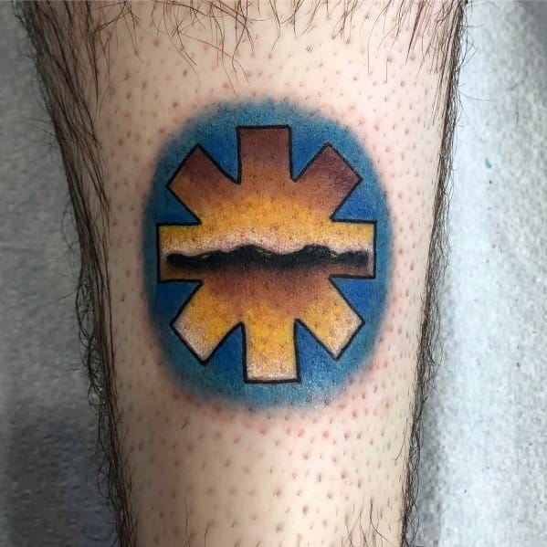 Tattoo featuring the Red Hot Chili Peppers logo filled with a sunset landscape, blending warm orange and cool blue tones for a vibrant look.