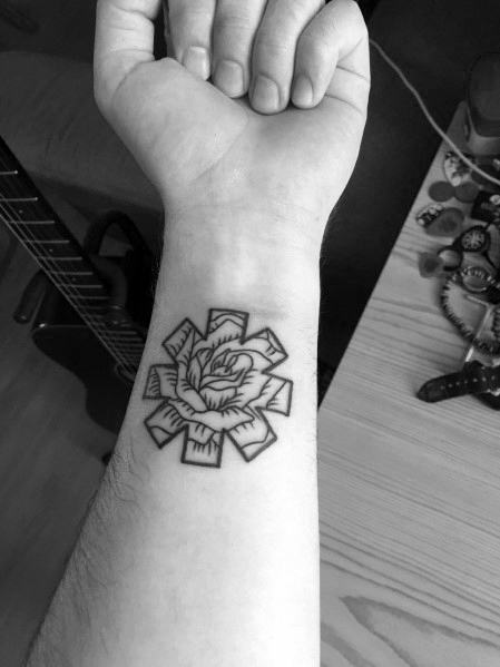 Wrist tattoo featuring the Red Hot Chili Peppers logo with a detailed rose design inside, blending bold lines with floral artistry.