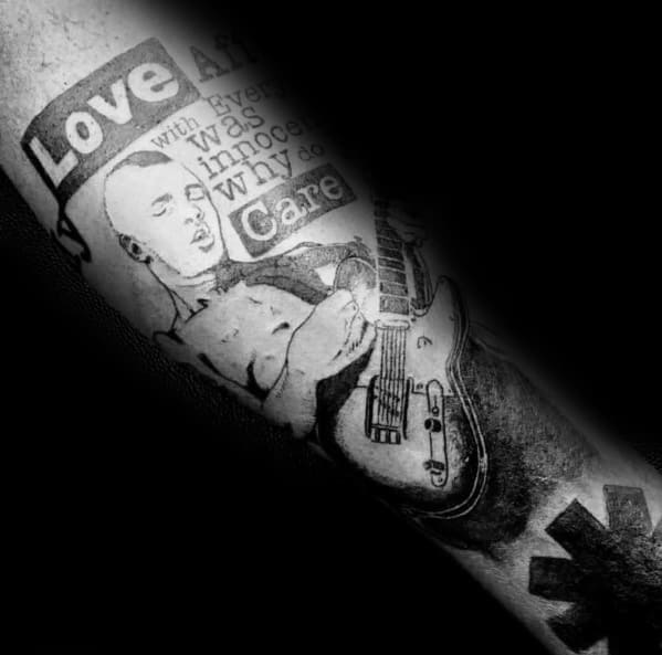 Black and grey tattoo featuring a detailed portrait of a bassist playing, with song lyrics and the Red Hot Chili Peppers logo for a bold tribute.