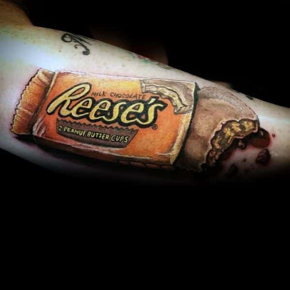 Hyperrealistic Reese’s Peanut Butter Cups tattoo with detailed shading and texture, featuring a bitten chocolate piece for a striking 3D effect.