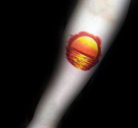 Tattoo of a vibrant sunset reflecting on the ocean, featuring warm hues and a watercolor effect for a serene and artistic design.