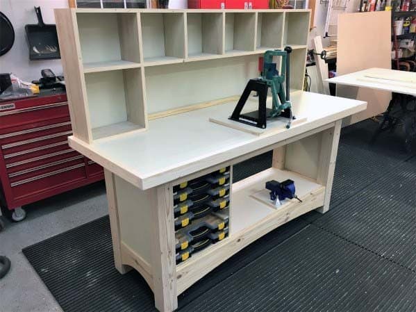 Sturdy custom-built reloading bench with upper storage shelves, mounted press, and organized lower compartments for tools