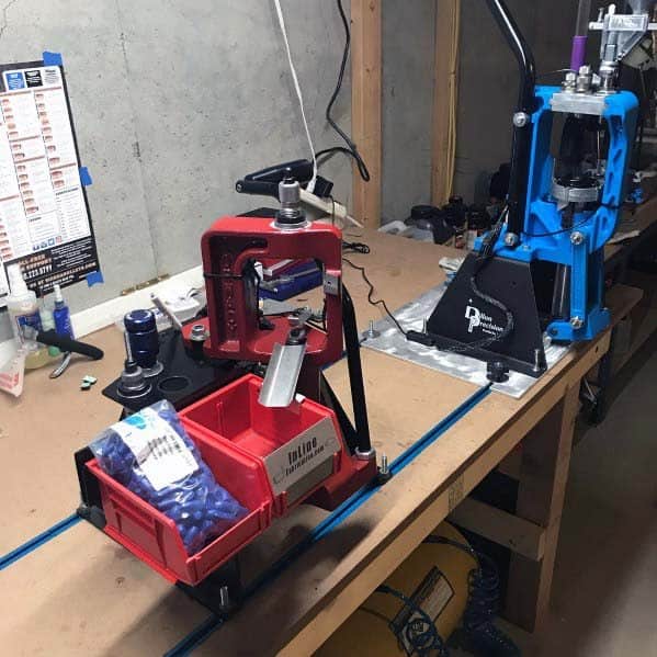 Reloading bench with mounted red and blue presses, organized bins for bullets, and a solid wooden workspace ideal for precision tasks