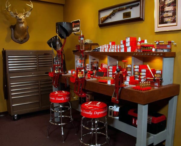 Red reloading station with matching stools and a wall-mounted rifle display.
