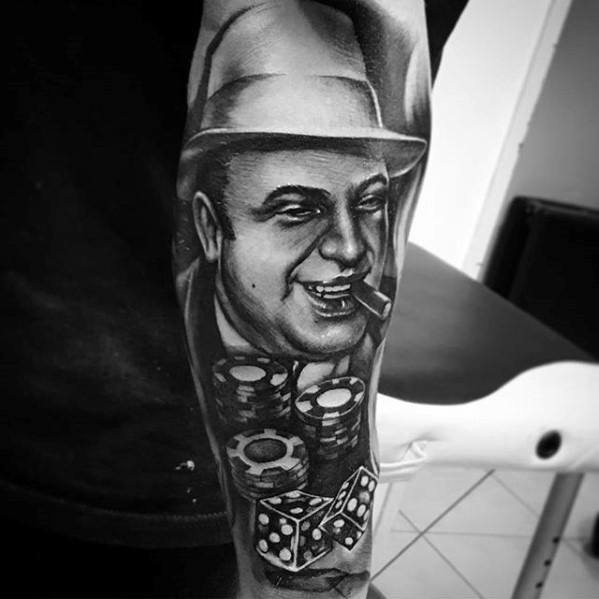 Al Capone tattoo featuring a black-and-white portrait of the gangster smiling with a cigar, surrounded by stacks of casino chips and dice, capturing his association with the world of organized crime and gambling.
