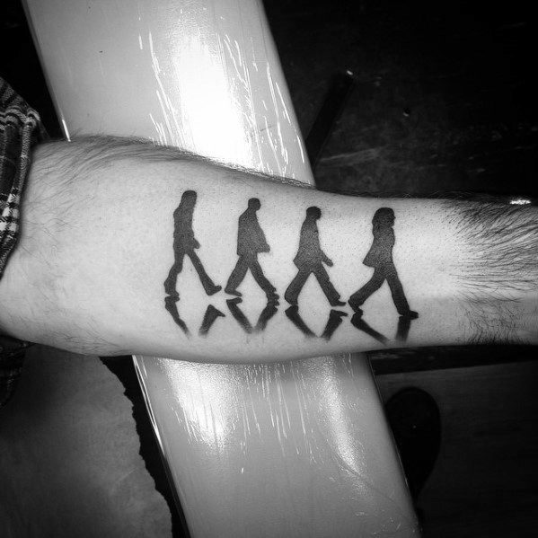 Silhouette tattoo of The Beatles crossing Abbey Road with mirrored reflections beneath each figure for a dynamic visual effect.