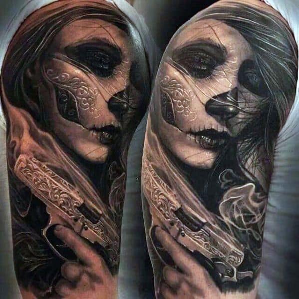 La Catrina tattoo of a woman with dark makeup holding an ornate pistol, detailed with smoke and rich black and grey shading.