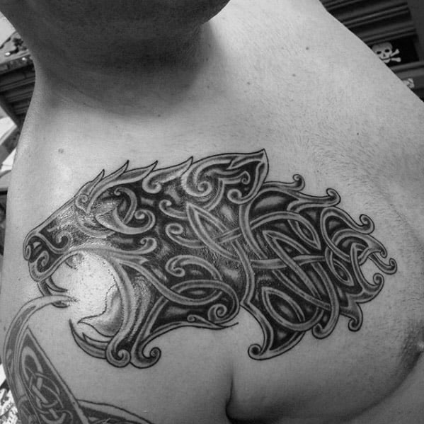 Celtic wolf head tattoo on chest with bold, flowing knotwork and detailed shading forming a fierce and decorative silhouette.