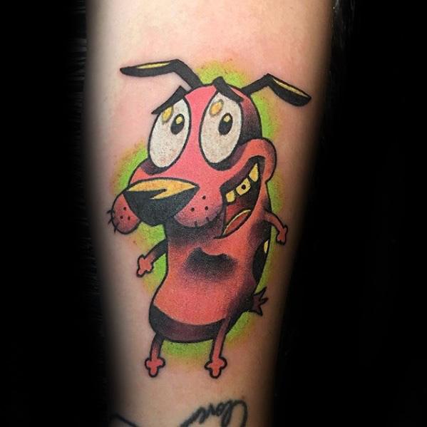 Courage the Cowardly Dog tattoo with a nervous smile and wide eyes, highlighted by a glowing green background and bold shading.