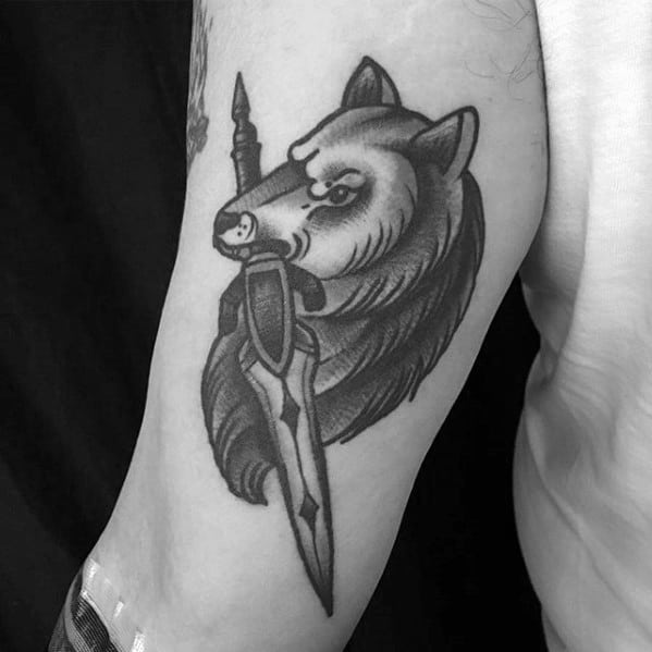 Traditional blackwork tattoo of Sif the Great Grey Wolf from Dark Souls, holding a sword in its mouth with bold shading.