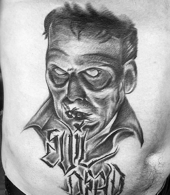 Black and grey Evil Dead tattoo of a sinister undead face with hollow eyes, paired with stylized “Evil Dead” lettering below in a bold gothic font