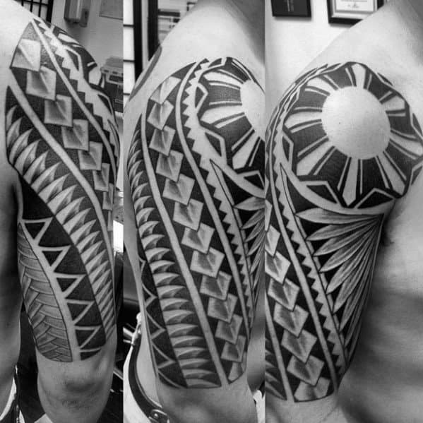 Filipino sun tattoo on the shoulder with bold geometric rays and deep-shaded tribal patterns wrapping around the upper arm in a half-sleeve style.