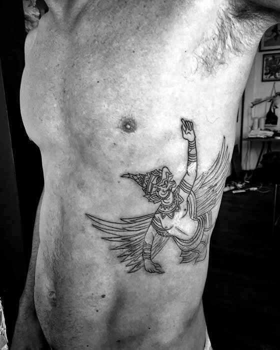 Garuda tattoo outline on the side torso, showing a winged figure with raised arm and traditional headdress in a minimal black line style.