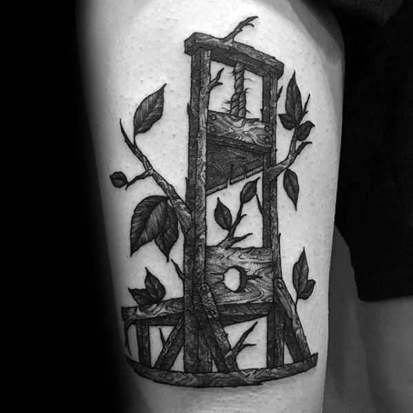 Intricate black and grey guillotine tattoo with realistic wood texture, overgrown vines, and leaves weaving through the structure.