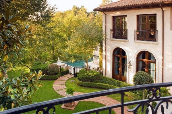 Serene brick pathway meandering through a lush garden, leading to a luxurious pool area beside a beautiful home
