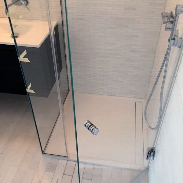 Minimalist bathroom with a corner glass shower door, chrome fixtures, a white sink, and light gray tiles