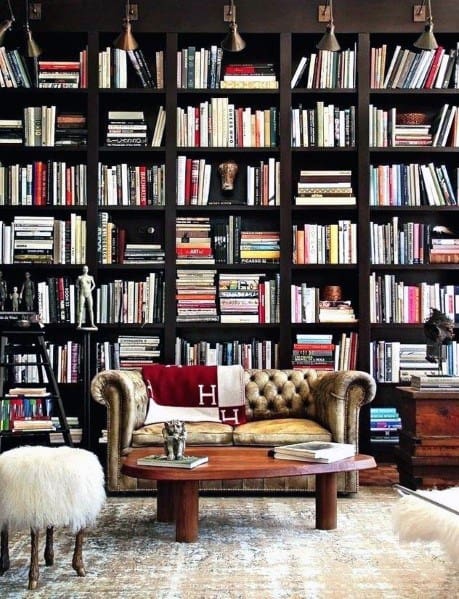 Cozy library with a bookshelf, sofa, coffee table, and fluffy stool