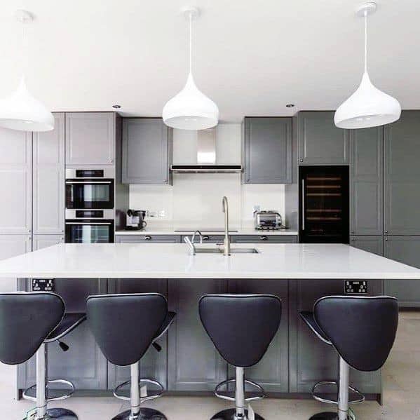 Contemporary grey kitchen with white island, black bar stools, and modern pendant lights.