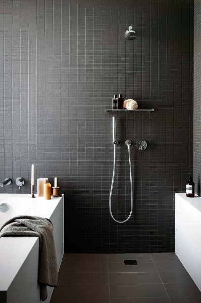 Modern bathroom with dark floor tiles, a rainfall showerhead, candles, and bath products