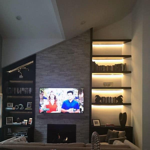 Modern living room with TV, stacked stone shelves, and a cozy fireplace