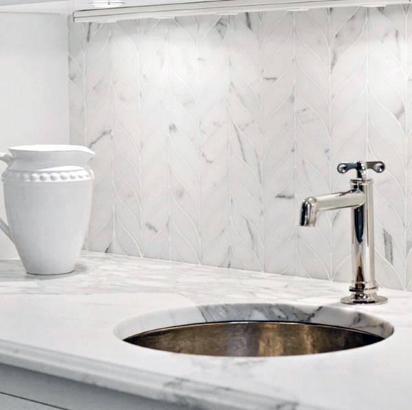 Elegant kitchen with a leaf-patterned marble backsplash, polished chrome faucet, and a seamless marble countertop