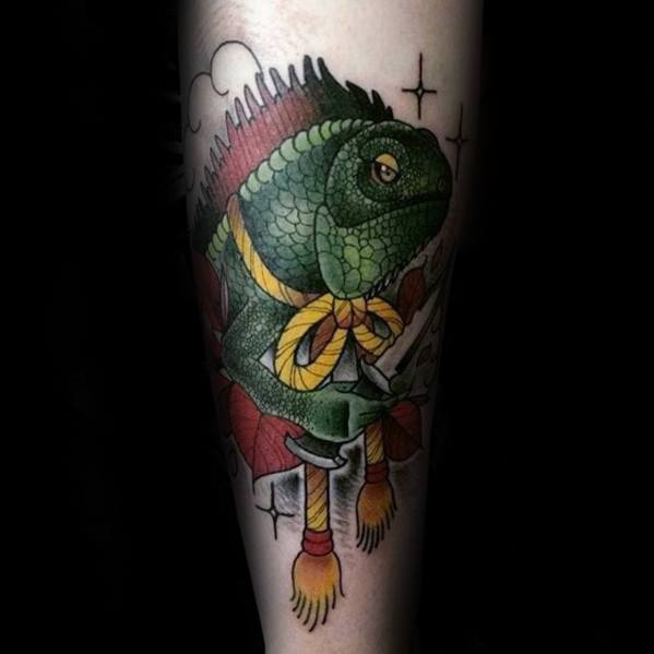 Traditional-style iguana tattoo wearing a yellow bow, sitting on fireworks with bold outlines, vibrant colors, and star accents.
