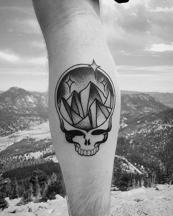 Grateful Dead Steal Your Face skull tattoo with geometric mountain peaks and stars, done in black and grey dotwork style.