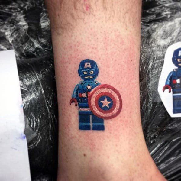 Colorful tattoo of a Lego Captain America minifigure holding his iconic shield, placed on the lower leg with bright, clean detailing.