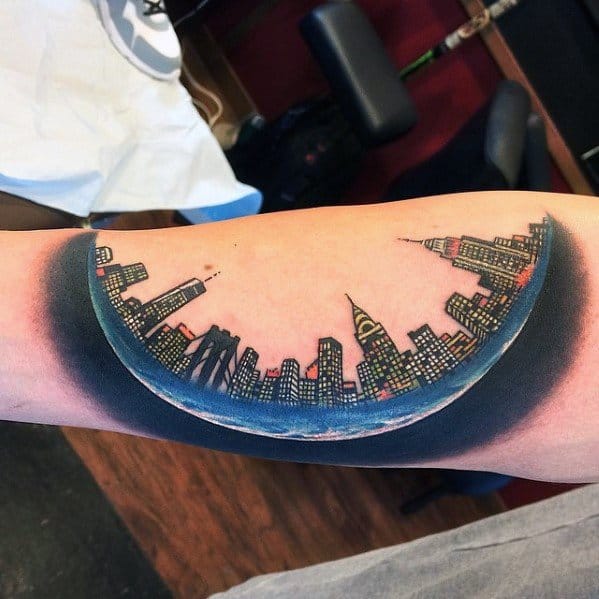 Colorful inner forearm tattoo of the New York City skyline set inside a crescent moon with night sky shading.