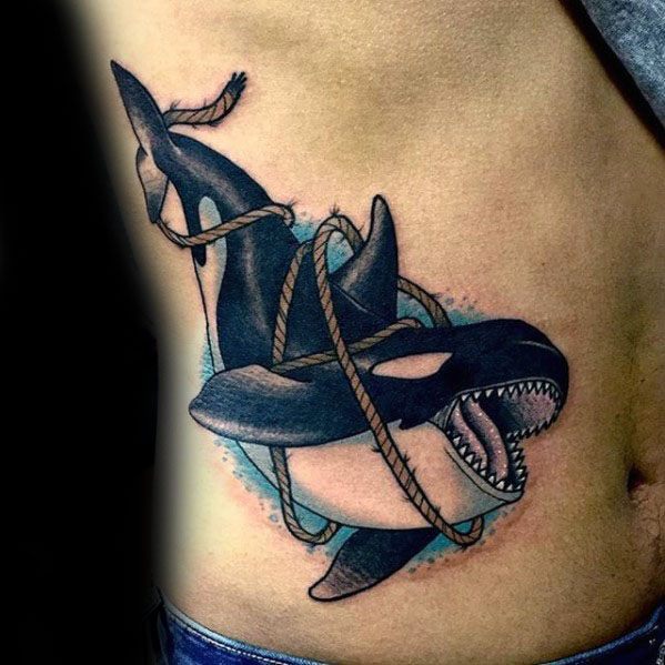 Colorful tattoo on the side, depicting an orca whale with ropes tangled around its body, showcasing bold black shading and light blue accents for contrast.