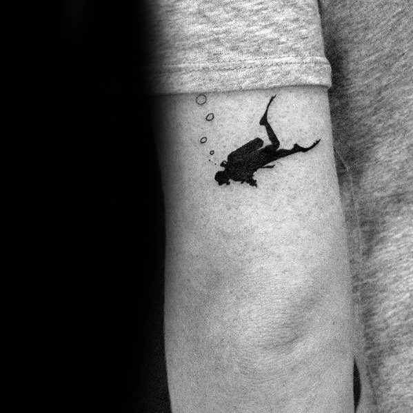 Minimalist black scuba diver tattoo on arm, showing diver swimming with air bubbles rising above.