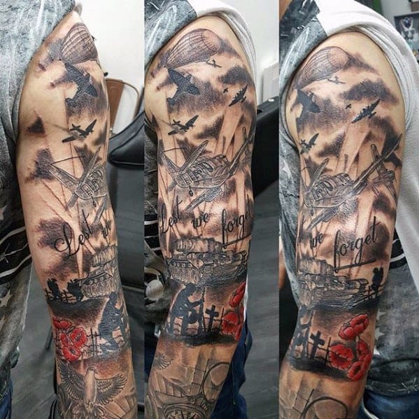 Full sleeve war tribute tattoo with tanks, planes, crosses, red poppies, and “Lest We Forget” text, honoring fallen soldiers in dramatic style.