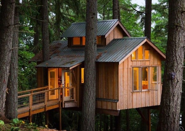 A cozy treehouse nestled among tall trees, with glowing windows and a wooden bridge leading to the entrance