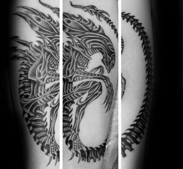 Intricate black and grey Xenomorph tattoo in a crouching pose with sharp tribal-like patterns and a long segmented tail wrapping around.