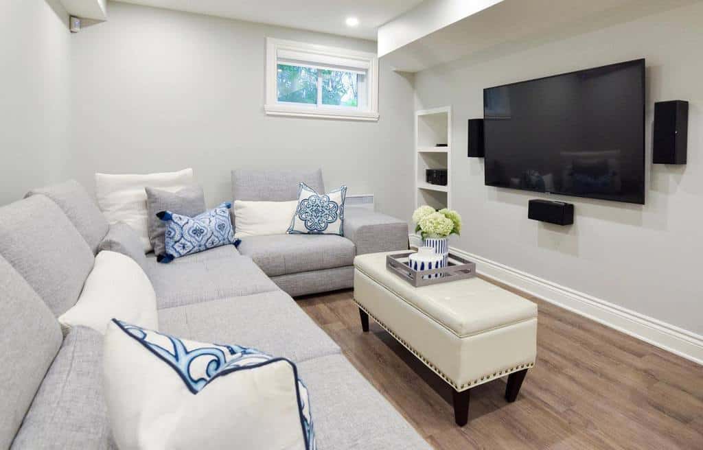 small white living room with gray sofa and wall mounted tv