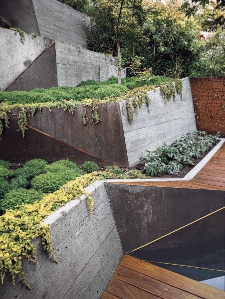 Modern concrete retaining walls with cascading greenery and adjacent wooden decking.