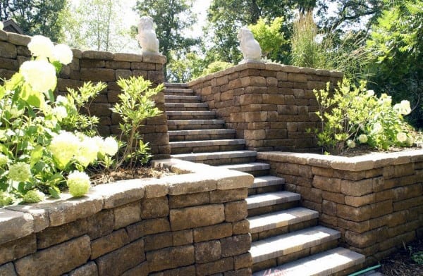 Stone retaining walls with central stairs, decorative lion statues, and flowering plants.