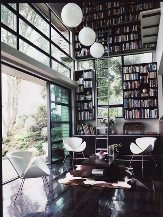 Modern library with high bookshelves, large windows, ladder, white chairs, and a dark glossy floor