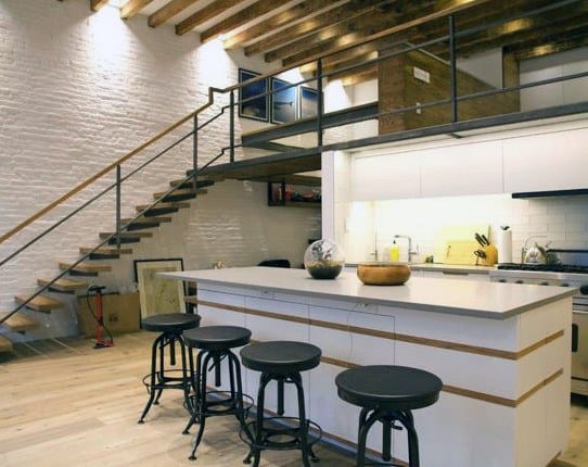 Rustic loft with exposed beams, white brick walls, and open kitchen with bar seating.