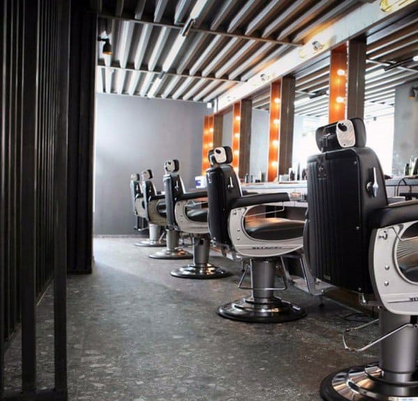 Industrial-style barbershop with retro chairs and illuminated mirrors.