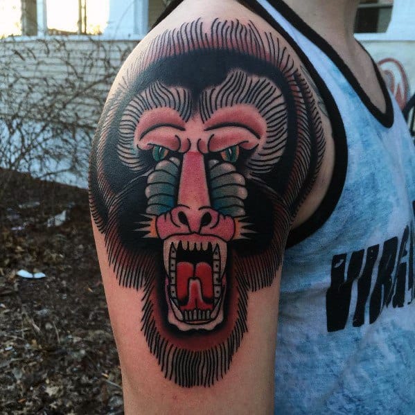 Traditional-style baboon tattoo with bold outlines, vivid colors, and a fierce open-mouthed expression, creating a striking and powerful shoulder design.