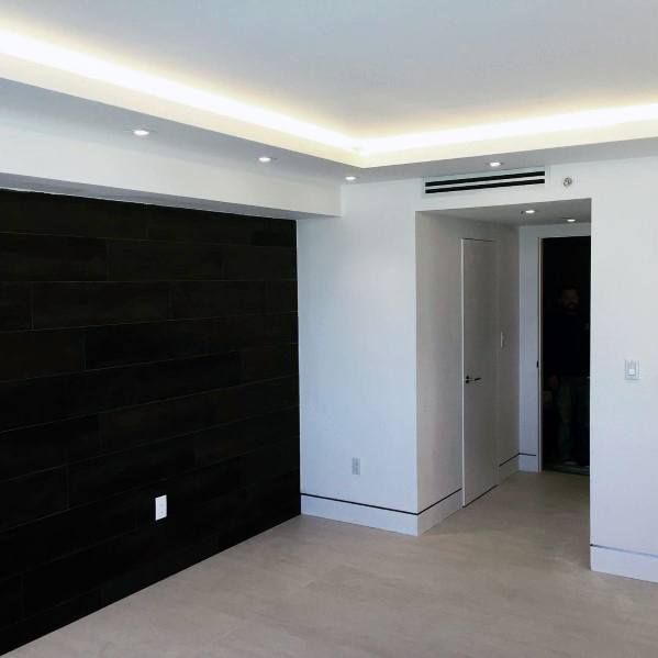 Modern room with recessed lighting, dark accent wall, and reveal bead baseboards on light flooring.