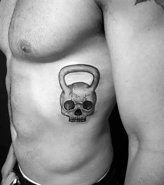 Realistic black and gray kettlebell skull tattoo on the ribs, symbolizing strength, endurance, and a fearless dedication to fitness and CrossFit.