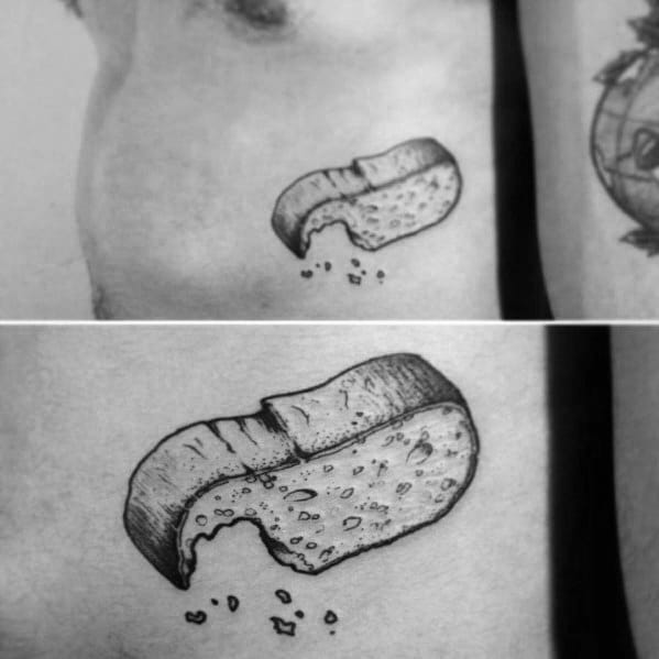 Black ink tattoo of a bitten bread loaf with scattered crumbs, featuring fine shading and texture for a realistic and playful design.