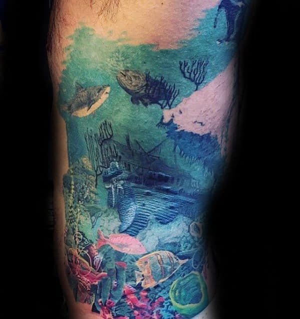 Colorful underwater tattoo featuring a sunken ship, scuba diver, mermaid, coral reef, and various tropical fish in a vivid ocean scene.