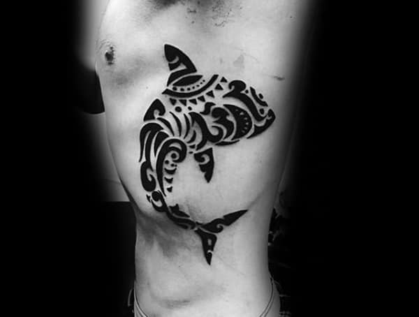 Side torso tattoo for men featuring a bold tribal-style shark design in solid black ink.