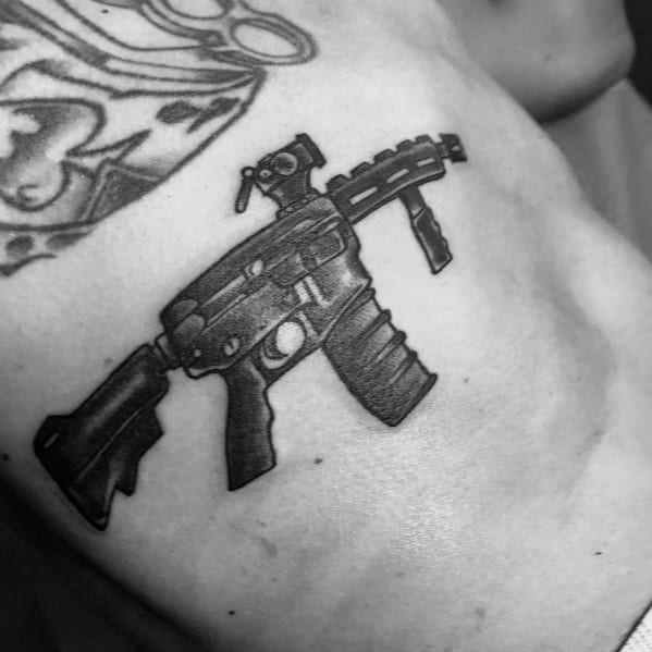 Small black and grey AR-15 tattoo on the ribcage, featuring bold shading and a compact design, symbolizing strength, precision, and firearm appreciation.