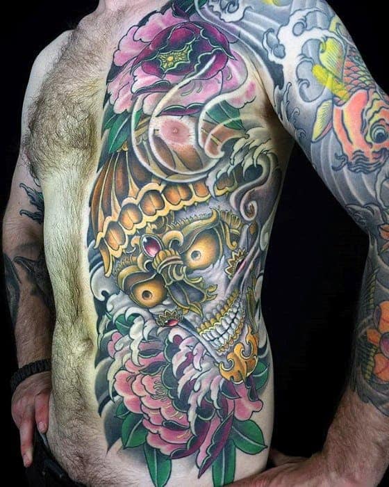 Man with vibrant full torso and arm tattoos featuring a skull and various flowers