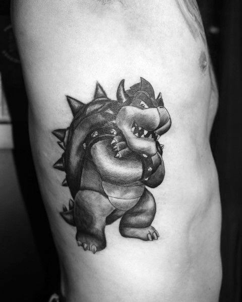 Black and grey Bowser tattoo on a man's ribcage featuring bold shading, strong contrast, and a classic pose for a striking Mario-inspired design.